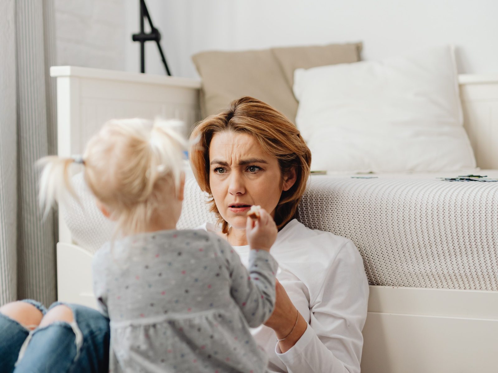 Eine Mutter sitzt mit ihrer kleinen Tochter auf dem Boden und wirkt angespannt