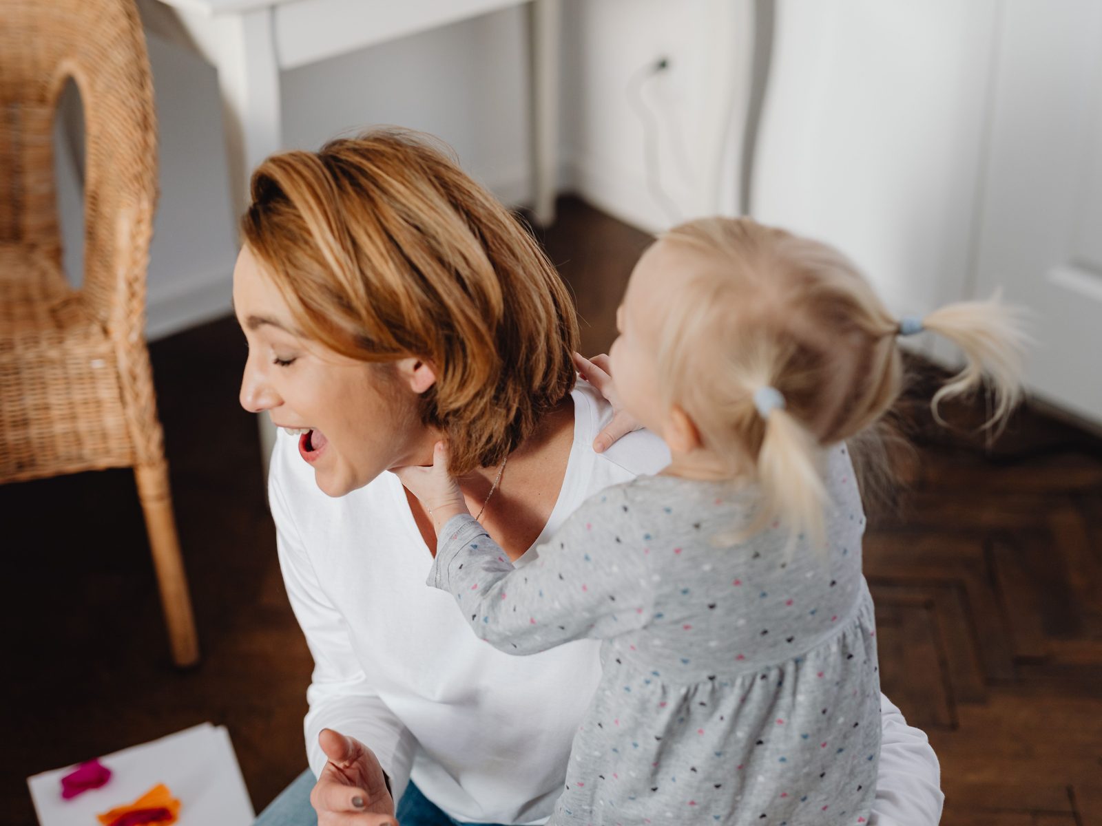 Eine Mutter lacht, während ihre Tochter sich von hinten an sie lehnt