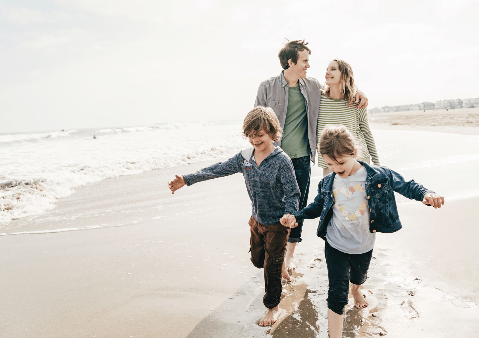 Eine Familie geht barfuß am Strand entlang